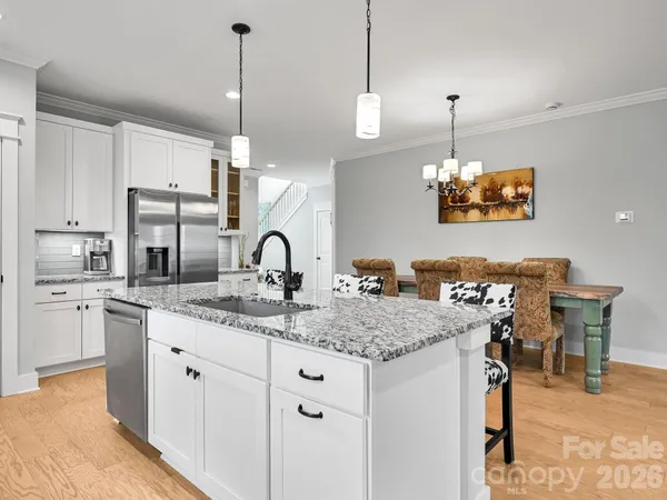 a kitchen with stainless steel appliances granite countertop a sink a stove and chairs