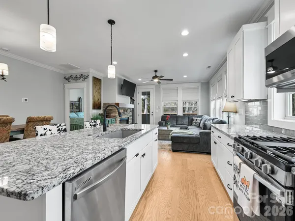 a large kitchen with kitchen island a stove a sink dishwasher a dining table and chairs with wooden floor