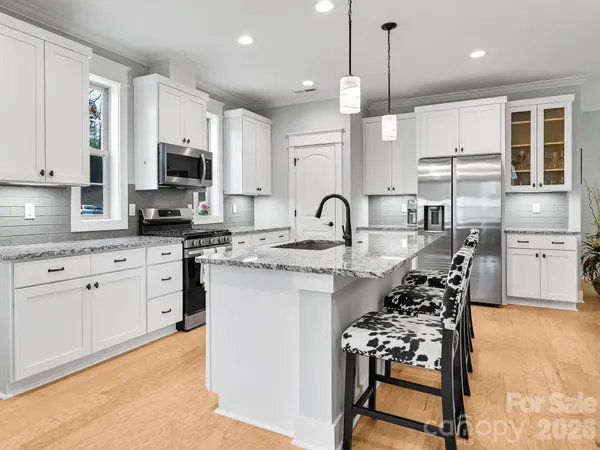 a kitchen with kitchen island granite countertop a sink counter top space appliances and cabinets