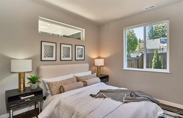 a bedroom with bed a lamp and a large window