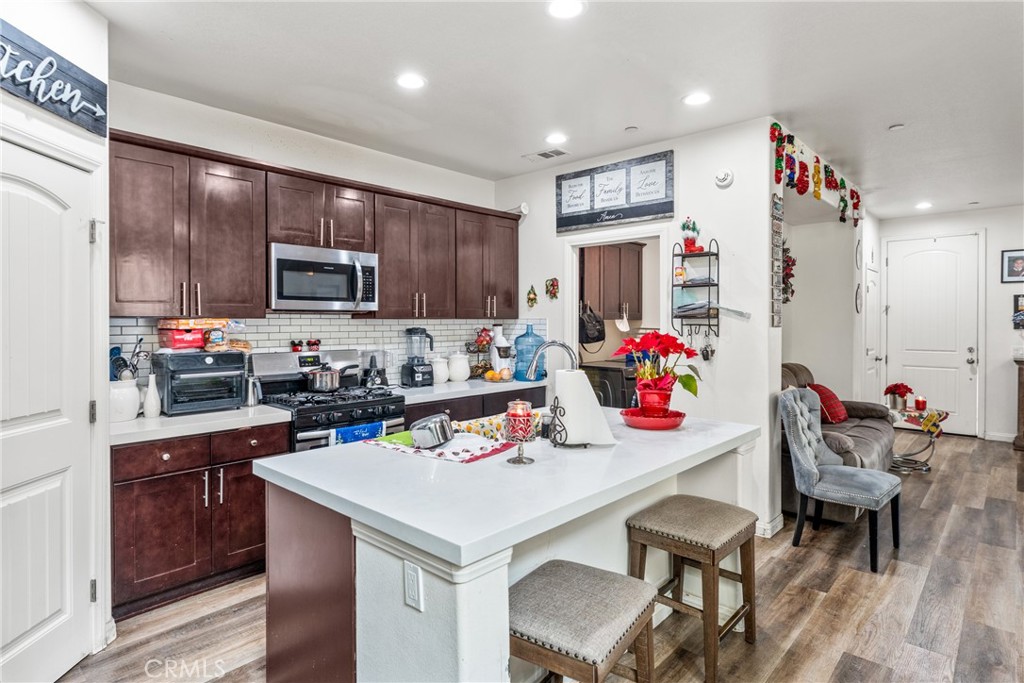 507 Villa Way Colton, CA 92324 - Photo 11 of 34 a kitchen with a refrigerator a stove and a dining table with wooden floor