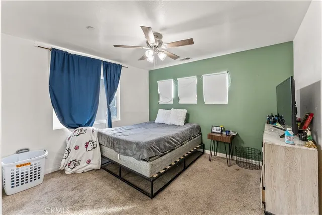 a bedroom with a bed a chandelier and a dresser