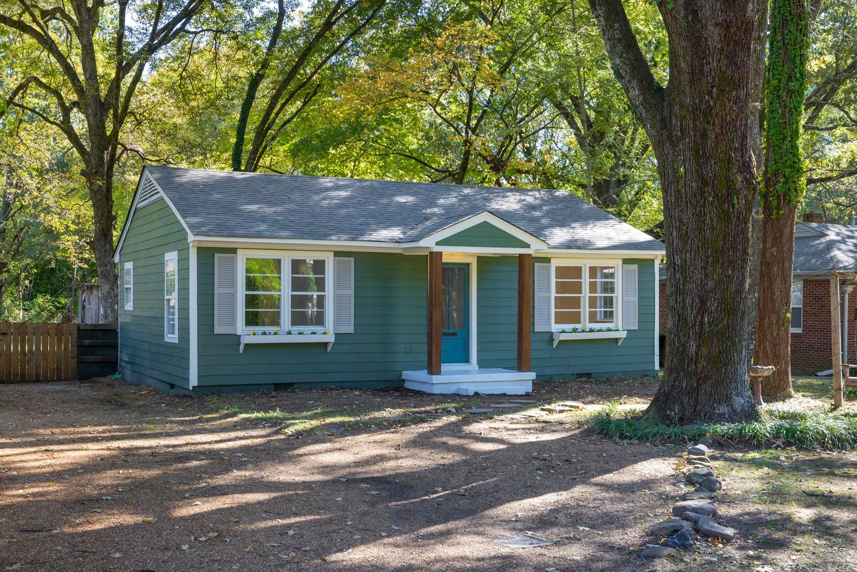 a front view of a house with a garden and tree