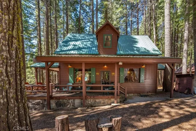 a view of a house with large tree and wooden fence