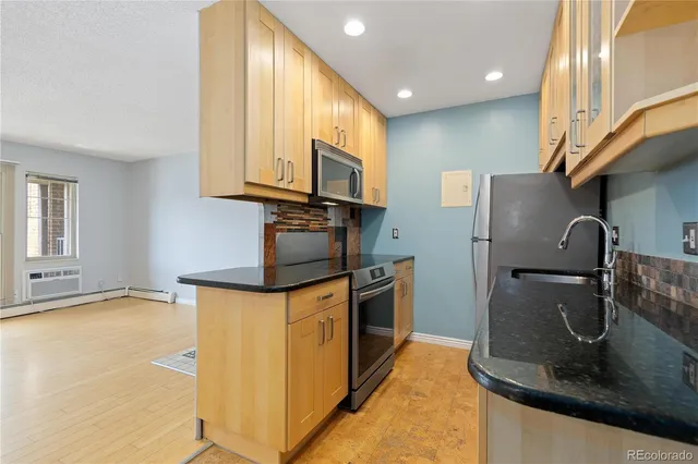 a kitchen with stainless steel appliances granite countertop a refrigerator a stove and a sink with wooden floor