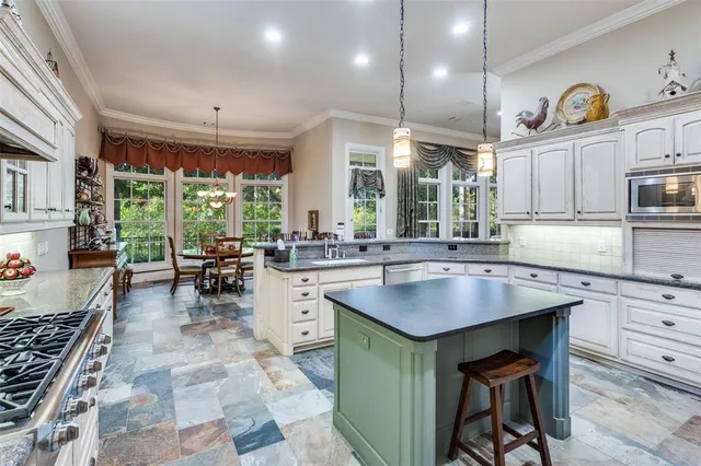 a kitchen with kitchen island granite countertop a sink a counter top space appliances and cabinets