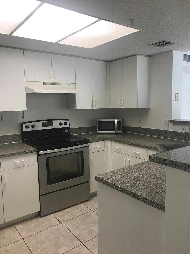 5025 Wiles Road, Unit 207 Coconut Creek, FL 33073 - Photo 1 of 6 a kitchen with granite countertop a stove sink and cabinets