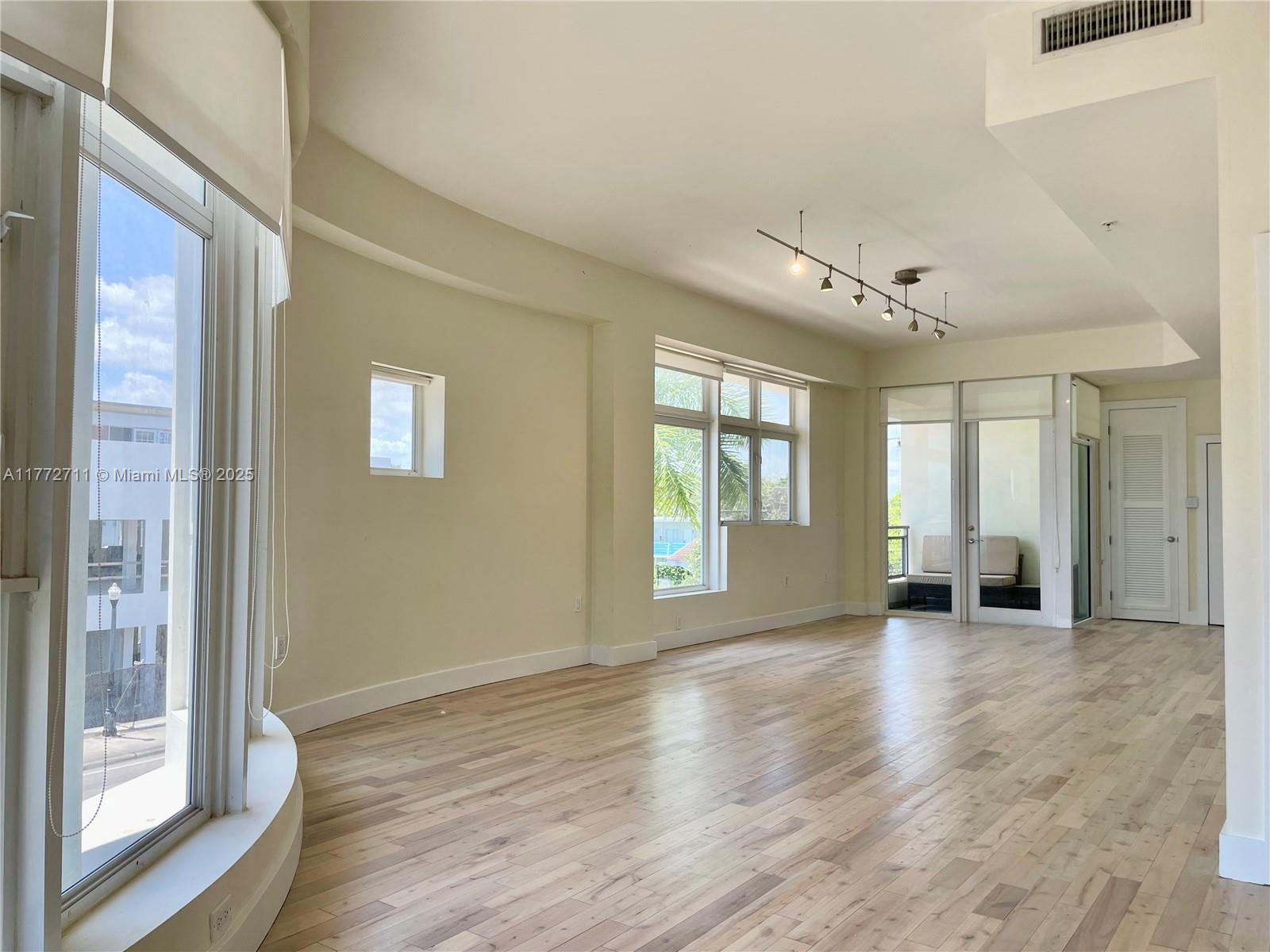 6701 Biscayne Boulevard, Unit 201 Miami, FL 33138 - Photo 6 of 22 a view of an empty room with a window and wooden floor