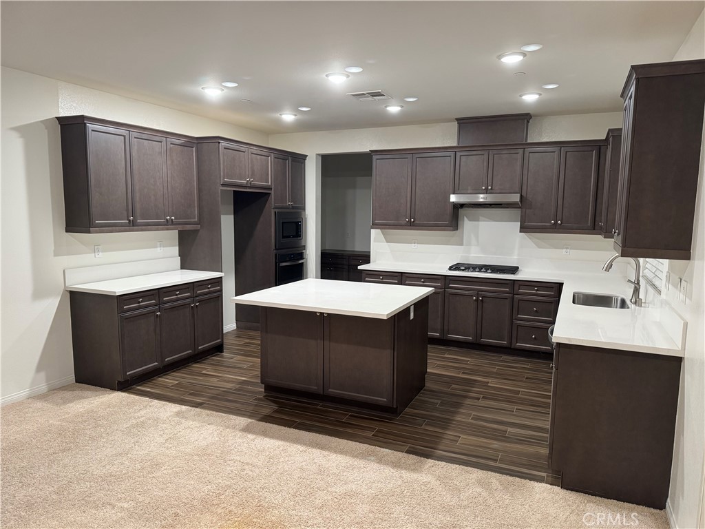 28582 Buttercup Way Moreno Valley, CA 92555 - Photo 9 of 55 a large kitchen with stainless steel appliances kitchen island granite countertop a stove a refrigerator and a sink with wooden cabinets