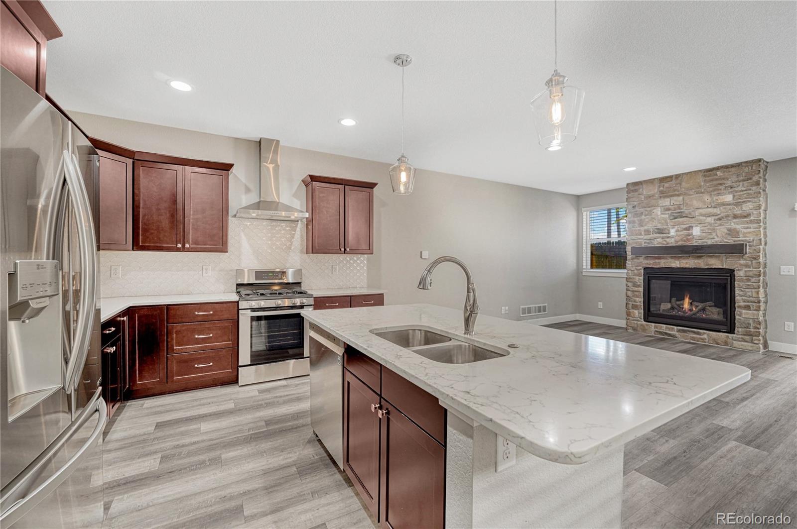 a kitchen with stainless steel appliances granite countertop a sink stove refrigerator and cabinets