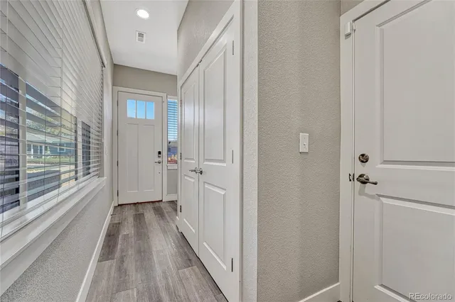 a view of a hallway with wooden floor and a bathroom