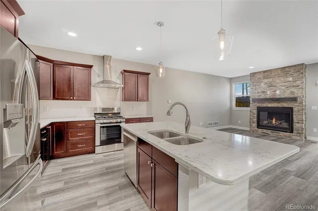 a kitchen with stainless steel appliances granite countertop a sink stove refrigerator and cabinets