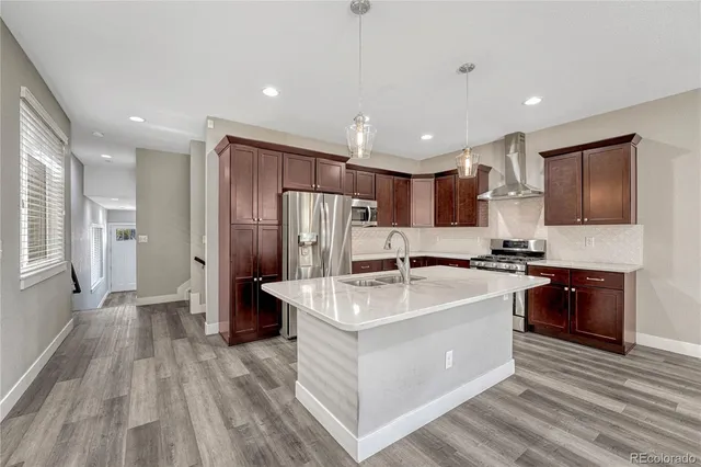 a large white kitchen with stainless steel appliances granite countertop a lot of counter space and wooden floors