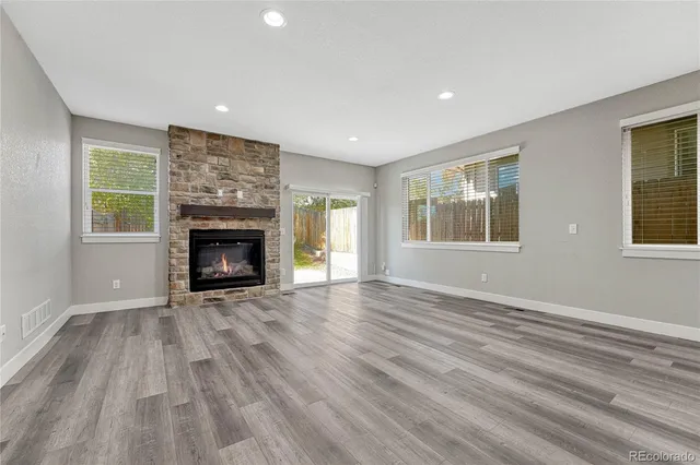 an empty room with windows and fireplace