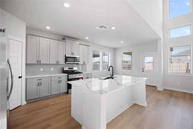 a large white kitchen with wooden floor and a sink