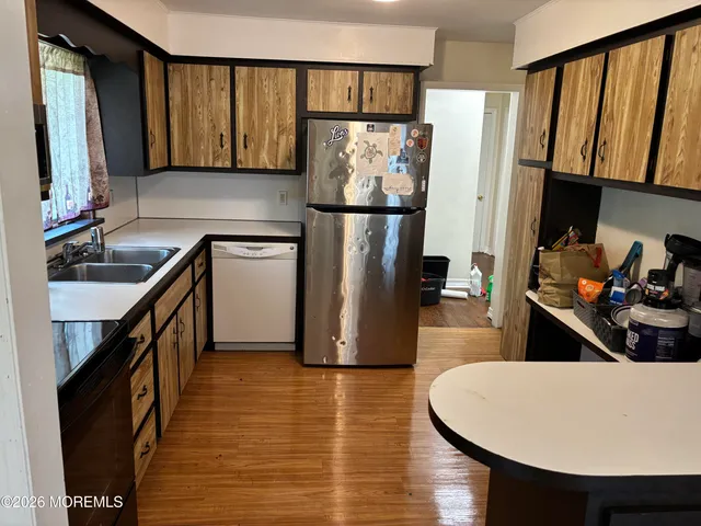 a kitchen with stainless steel appliances a refrigerator a sink a stove a dining table and chairs