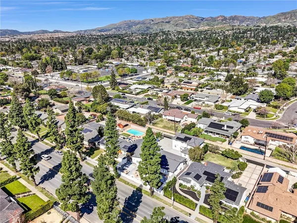 an aerial view of residential houses with outdoor space and trees