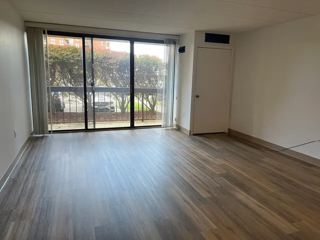 a view of an empty room with wooden floor and a window