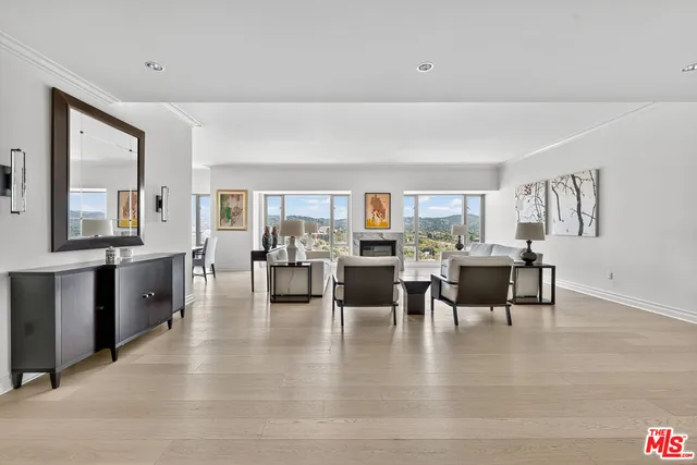 a living room with couches and kitchen view with wooden floor