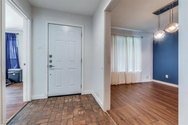 a view of an empty room with wooden floor and a bathroom