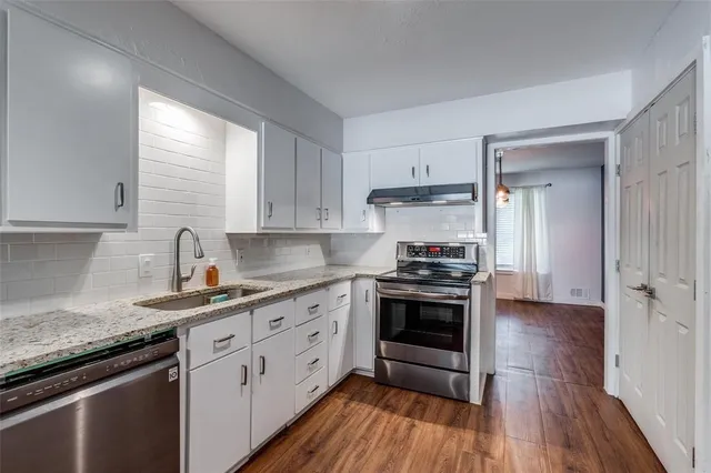 a kitchen with stainless steel appliances granite countertop a sink a stove and a refrigerator