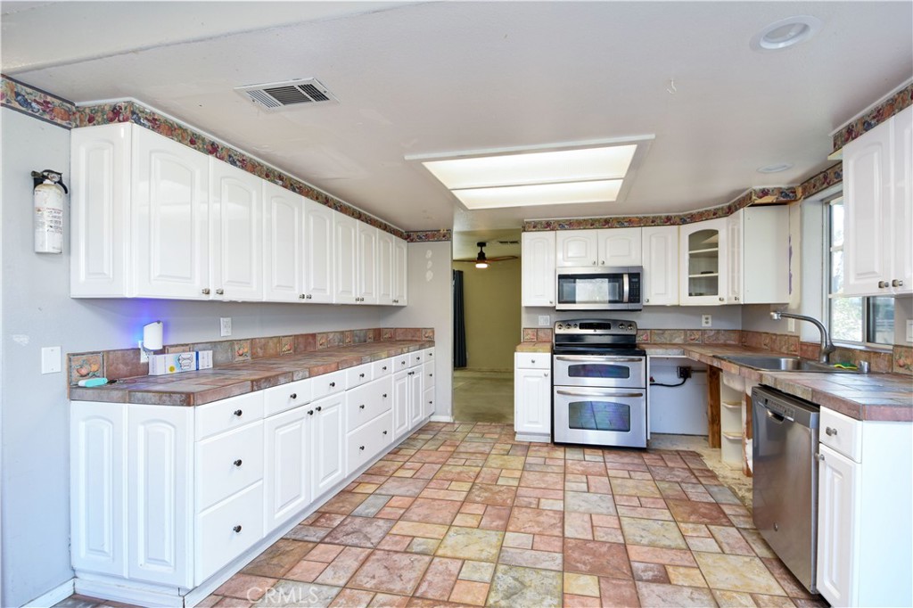 40520 Lake Riverside Drive Aguanga, CA 92536 - Photo 10 of 36 a large kitchen with stainless steel appliances granite countertop a stove top oven a sink dishwasher and white cabinets