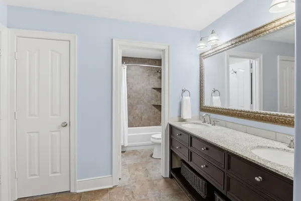a spacious bathroom with a double vanity sink a large mirror and a shower