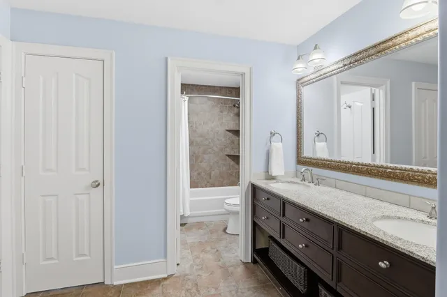 a spacious bathroom with a double vanity sink a large mirror and a shower