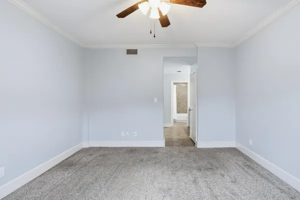an empty room with a ceiling fan and carpet