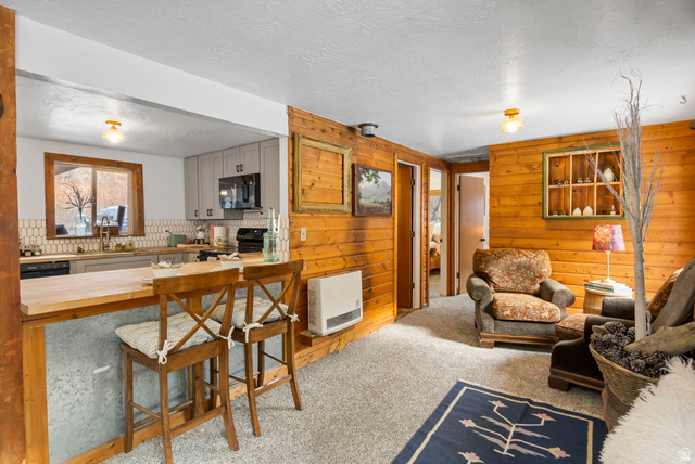 2189 Samak Park Loop, Unit 43 Kamas, UT 84036 - Photo 13 of 48 Living room with wood walls, light carpet, a textured ceiling, and heating unit