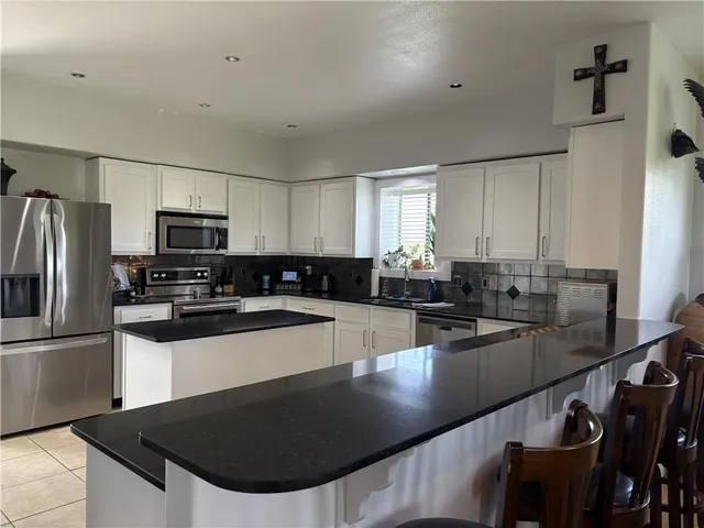 a kitchen with stainless steel appliances granite countertop a sink a stove a refrigerator a counter top space and cabinets