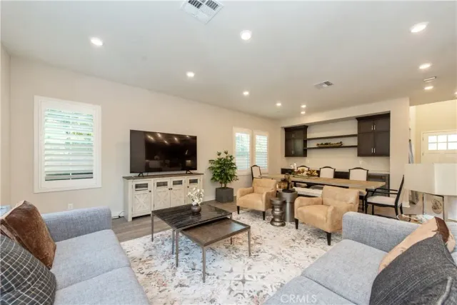 a living room with couches a coffee table and kitchen view with wooden floor