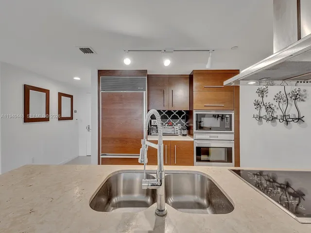 a kitchen with stainless steel appliances granite countertop a sink and a refrigerator