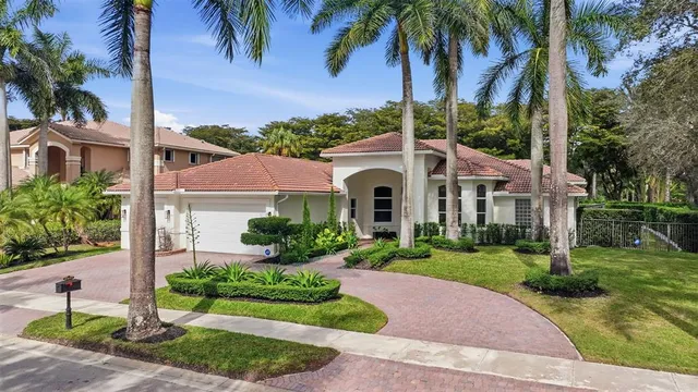a view of a white house with a yard and palm trees