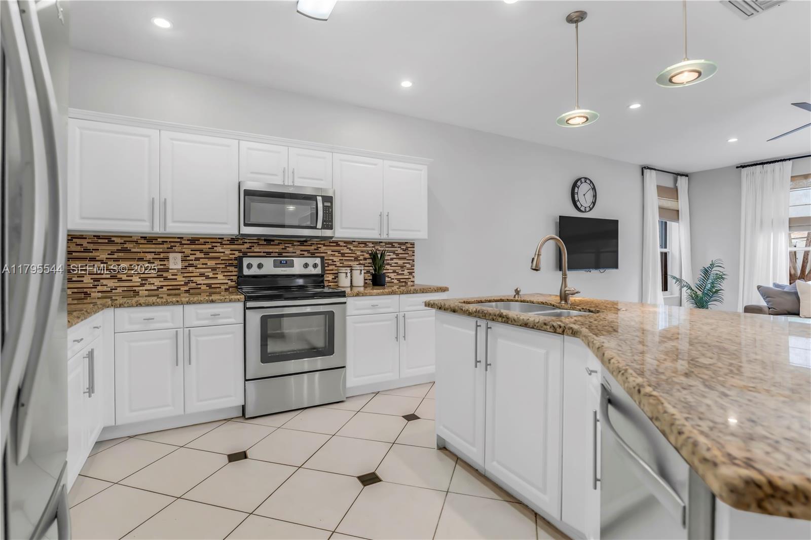 15862 Southwest 24th Street Miramar, FL 33027 - Photo 36 of 61 a kitchen with granite countertop a sink stainless steel appliances and white cabinets