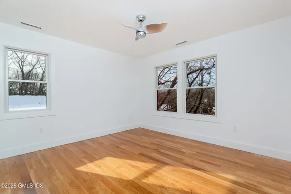 a view of a bedroom with wooden floor and a ceiling fan