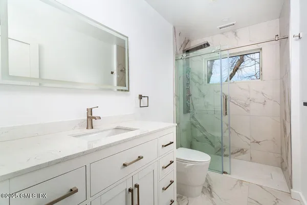 a bathroom with a sink a toilet and shower
