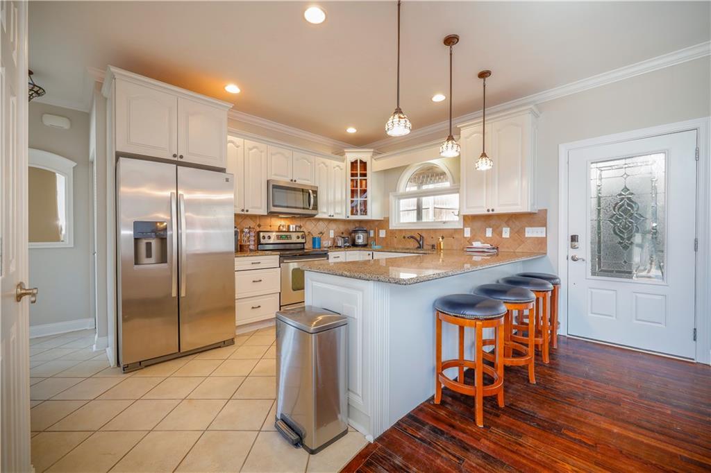 5997 Warpath Road Flowery Branch, GA 30542 - Photo 21 of 76 a kitchen with stainless steel appliances granite countertop a refrigerator a oven a sink a dining table and chairs with wooden floor