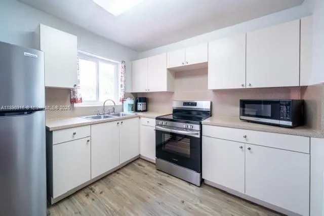 a kitchen with cabinets stainless steel appliances and sink