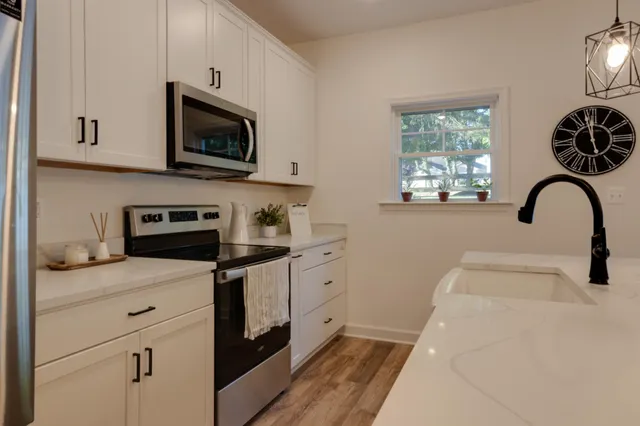 a kitchen with stainless steel appliances granite countertop a sink a stove a microwave and wooden cabinets