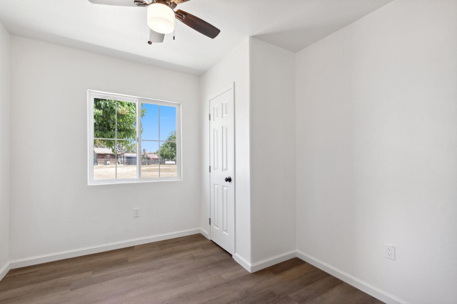 27747 Echo Road Madera, CA 93638 - Photo 21 of 38 an empty room with wooden floor chandelier fan and windows