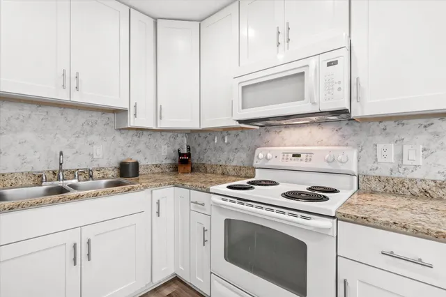 a kitchen with granite countertop white cabinets and white appliances