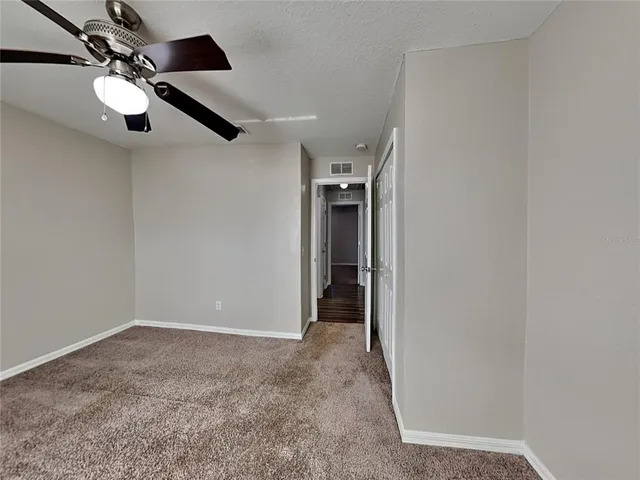 an empty room with a ceiling fan and carpet