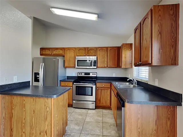 a kitchen with stainless steel appliances granite countertop a stove a sink dishwasher a refrigerator and a microwave