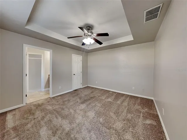 an empty room with chandelier fan and windows