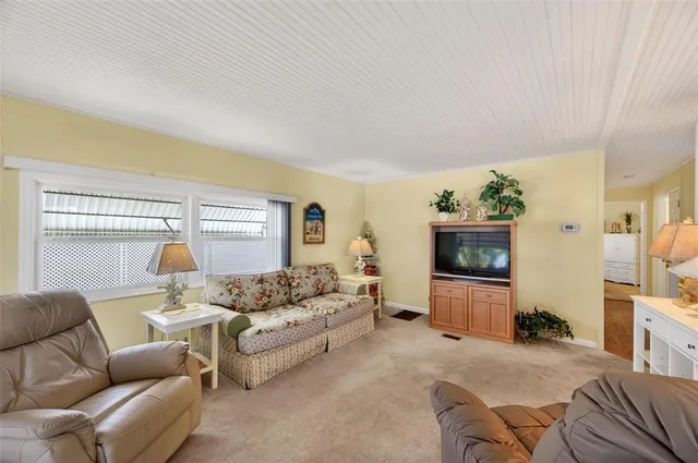 a living room with furniture a flat screen tv and a large window