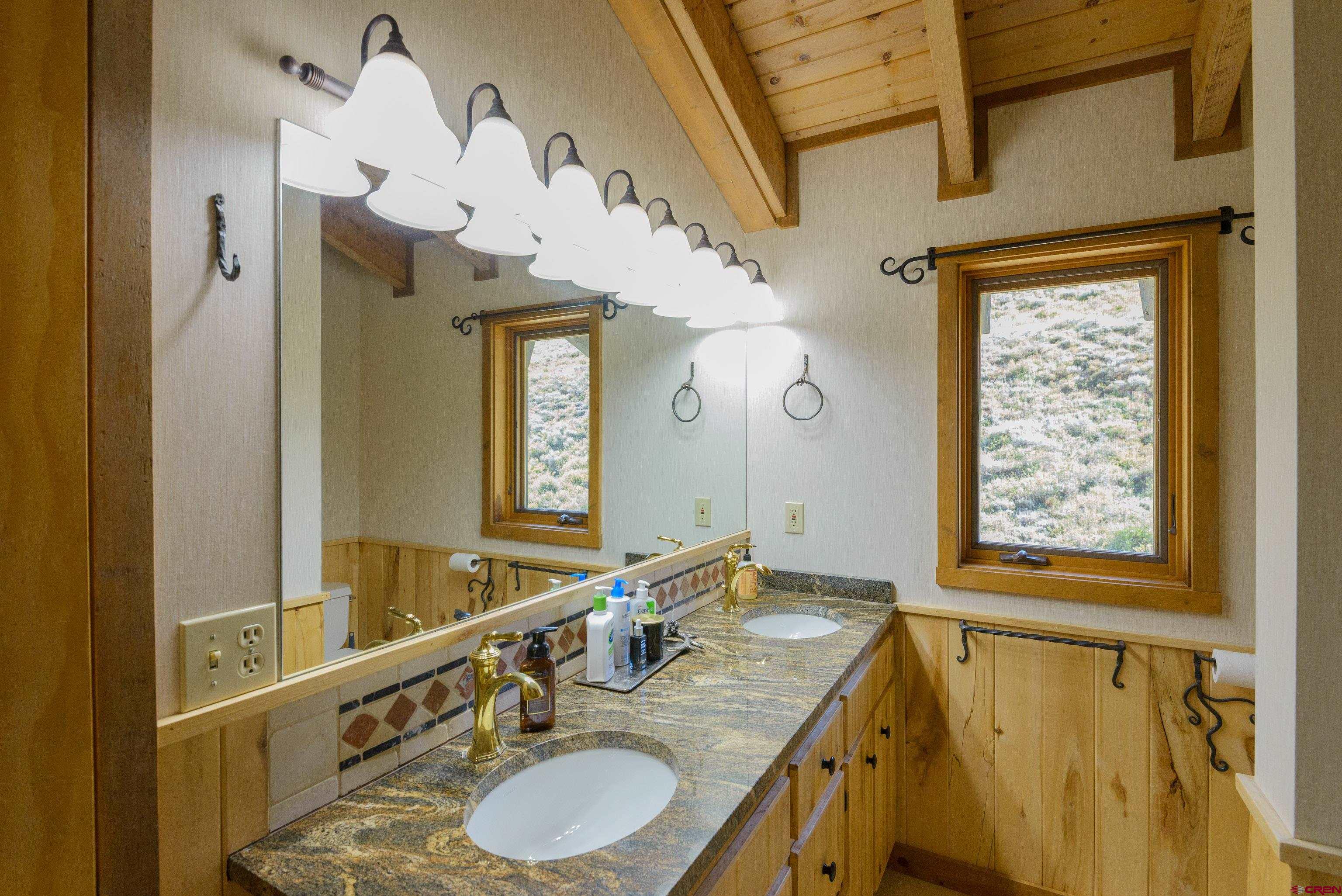 1250 County Road 734 Crested Butte, CO 81224 - Photo 32 of 45 a bathroom with a granite countertop double vanity sink and a mirror