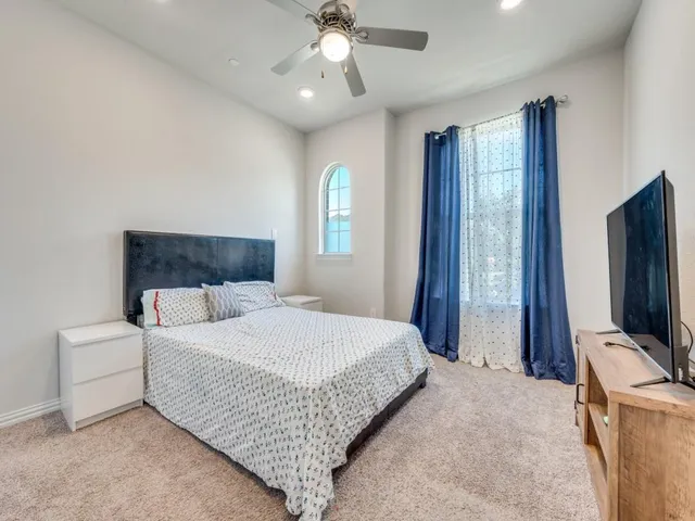 a bedroom with a bed and a flat tv screen on dresser