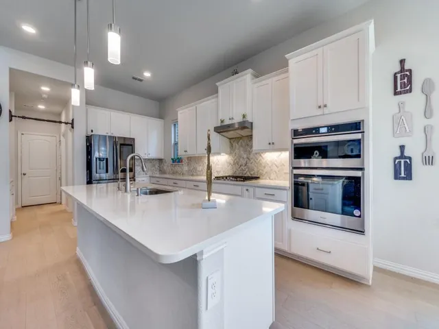 a kitchen with stainless steel appliances granite countertop a sink a stove and a refrigerator