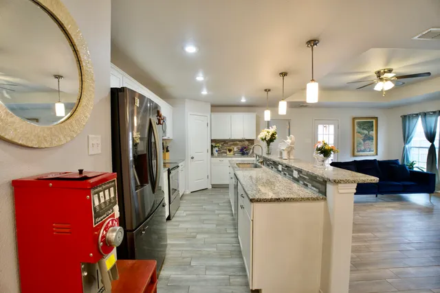 a large kitchen with stainless steel appliances kitchen island a stove a refrigerator a oven and a sink with large countertops